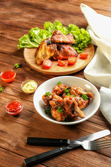 Tasty chicken and small bowls with sauces on wooden table