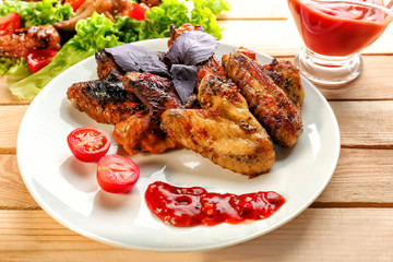Tasty chicken wings and gravy boat with sauce on wooden table
