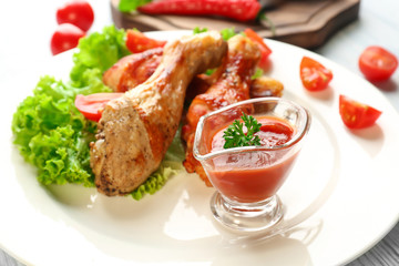 Tasty chicken legs and gravy boat with sauce on plate, closeup