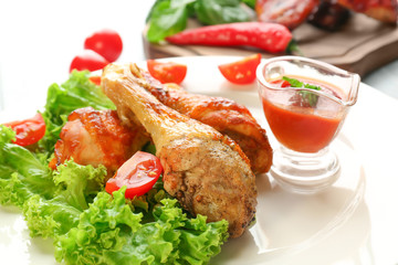 Tasty chicken legs and gravy boat with sauce on plate, closeup