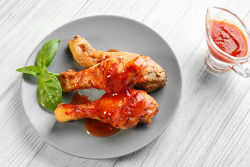 Tasty chicken legs with tomato sauce on wooden table
