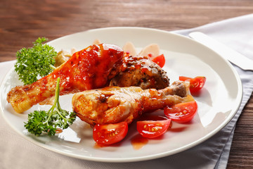 Tasty chicken legs with tomato sauce on plate, closeup