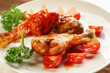 Tasty chicken legs with tomato sauce on plate, closeup