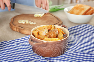 Baking dish with potatoes on table in kitchen. Cooking for one concept