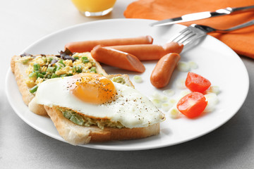 Plate with fried egg, sausages and toasts on table. Cooking for one concept