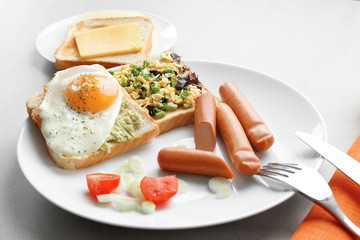 Plate with fried egg, sausages and toasts on table. Cooking for one concept