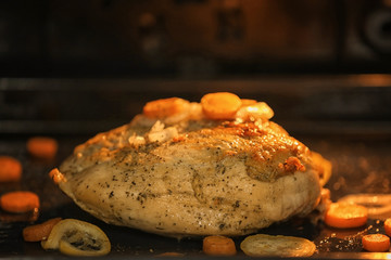 Baking tray with turkey breast cooking in oven, closeup