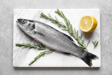 Fresh fish with rosemary and lemon on gray background