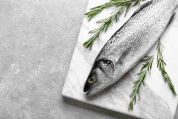 Fresh fish with rosemary on gray background