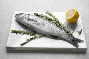 Fresh fish with rosemary and lemon on gray background