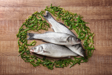 Fresh fish with chuka salad on wooden background