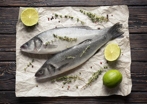 Fresh fish with thyme and lime on wooden background