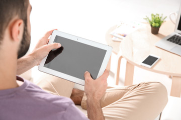 Young man searching information using tablet at home