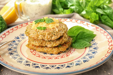 Broccoli pancakes served with grated cheese and basil leaves on patterned plate