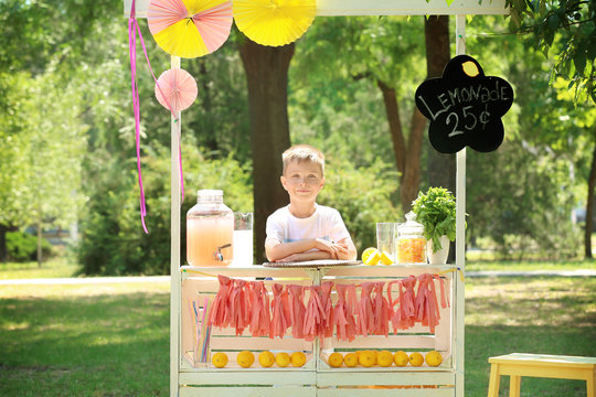 Cute little boy waiting for customers at lemonade stand in park