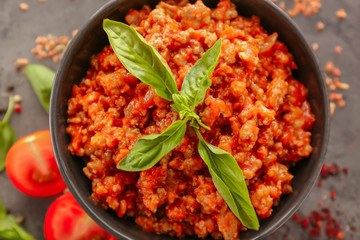 Composition with meat sauce, fresh tomatoes and basil leaves on grey background