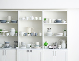 Fototapeta na wymiar White storage stand with ceramic dishware in kitchen