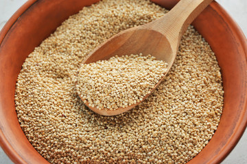 White quinoa and wooden spoon in bowl, closeup