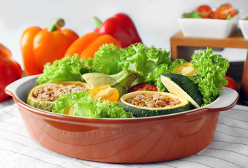 Quinoa stuffed zucchini served with salad and tomatoes on table