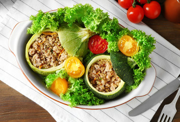 Quinoa stuffed zucchini served with salad and tomatoes on table