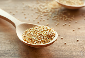 White quinoa in spoon on wooden background