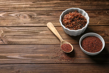 Bowls with raw and boiled quinoa grains on wooden table