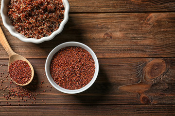 Bowls with raw and boiled quinoa grains on wooden table