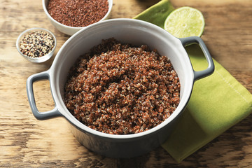 Pot with boiled quinoa grains on wooden table