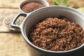 Pot with boiled quinoa grains on wooden table