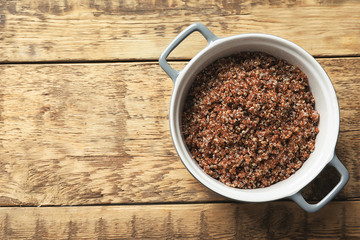 Pot with boiled quinoa grains on wooden table