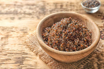 Bowl with boiled quinoa grains on wooden table