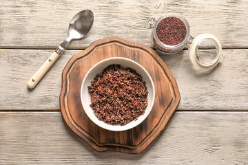 Bowl with boiled quinoa grains on wooden table