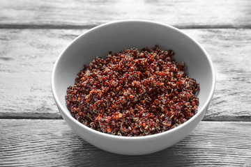Bowl with boiled quinoa grains on wooden table