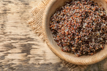 Bowl with boiled quinoa grains on wooden table