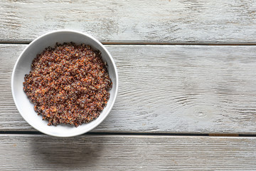 Obraz na płótnie Canvas Bowl with boiled quinoa grains on wooden table