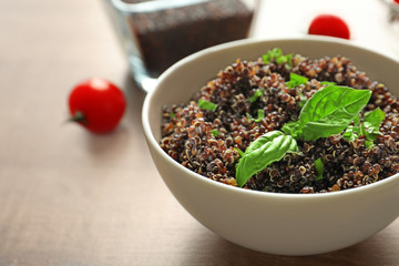 Bowl with boiled quinoa grains on wooden table