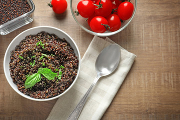 Bowl with boiled quinoa grains on wooden table