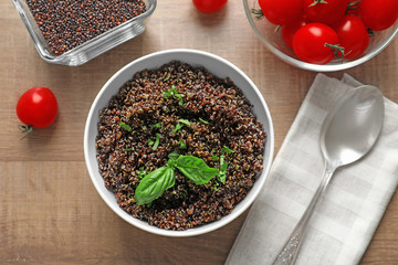 Bowl with boiled quinoa grains on wooden table