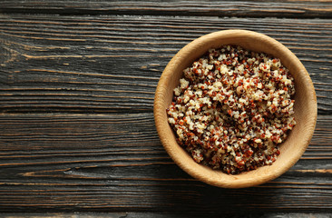 Bowl with boiled quinoa grains on wooden table