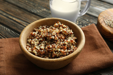 Bowl with boiled quinoa grains on wooden table