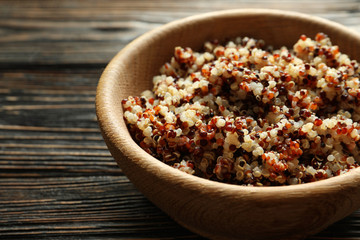 Bowl with boiled quinoa grains on wooden table