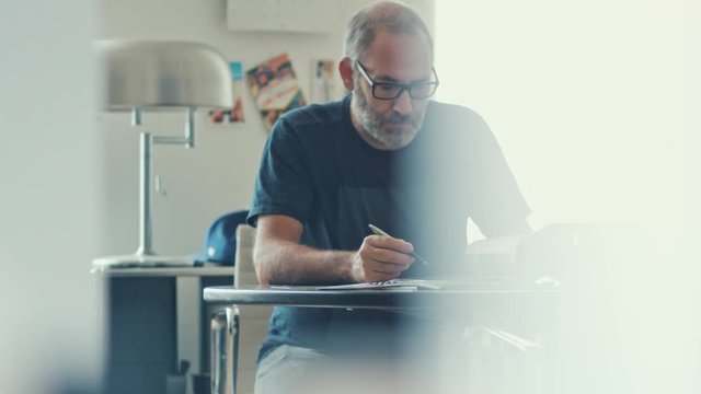 Narrow shot of a casual businessman working concentrated with his papers and documents on workdesk in modern office 
