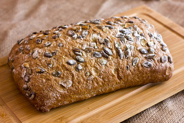Rye bread with pumpkin seeds on a wooden platter on burlap