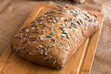 Rye bread with pumpkin seeds on a wooden platter on burlap