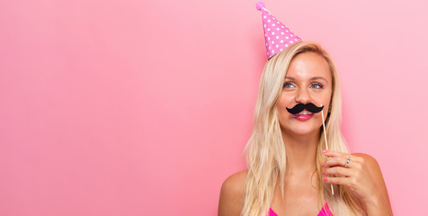 Young woman holding paper party sticks on a solid background