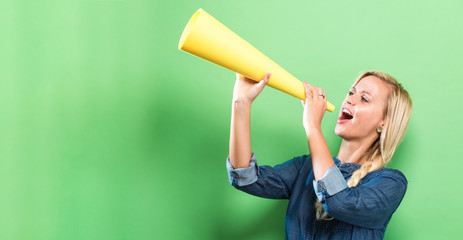 Young woman holding a paper megaphone on a solid background