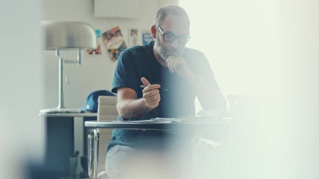 Narrow shot of a casual businessman working concentrated with his papers and documents on workdesk in modern office 