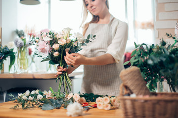 Smiling lovely young woman florist arranging plants in flower shop