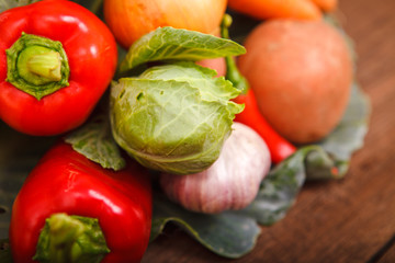 Fresh vegetables in a cabbage leaf on a wooden background. Chili, carrots, cabbage, potatoes, bell peppers and garlic on a wooden table. Thanksgiving Day. Background. Autumn harvest.