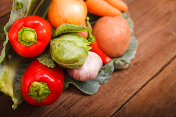 Fresh vegetables in a cabbage leaf on a wooden background. Chili, carrots, cabbage, potatoes, bell peppers and garlic on a wooden table. Thanksgiving Day. Background. Autumn harvest.